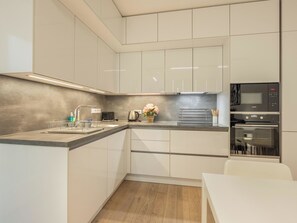A modern kitchen with white cabinets, a stainless steel countertop, and a built-in oven. - Nový Smíchov by Interhome (Smichov Kosire Jinonice)