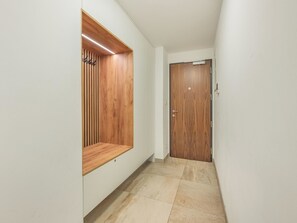 A hallway with a wooden bench, a door, and tiled flooring. - Nový Smíchov by Interhome (Smichov Kosire Jinonice)