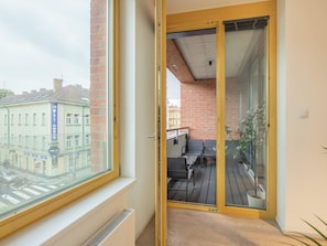 A balcony with a table and chairs, a view of the street, and a building with a sign. - Nový Smíchov by Interhome (Smichov Kosire Jinonice)