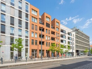 A multi-story building with a mix of brick and glass facades, a bike parking area, and a clear sky. - Nový Smíchov by Interhome (Smichov Kosire Jinonice)