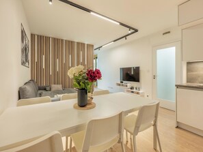 A modern living space with a dining area, a sofa, a TV, and a kitchen. - Nový Smíchov by Interhome (Smichov Kosire Jinonice)
