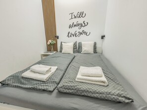 A neatly made twin bed with a grey quilt and pillows, a bedside table with a vase of flowers, and a wall with a motivational quote. - Nový Smíchov by Interhome (Smichov Kosire Jinonice)