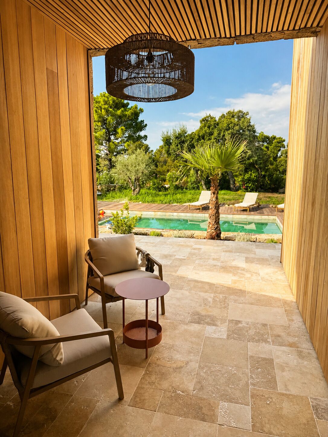 A wooden-framed patio with a pool, lounge chairs, and a hanging light fixture.