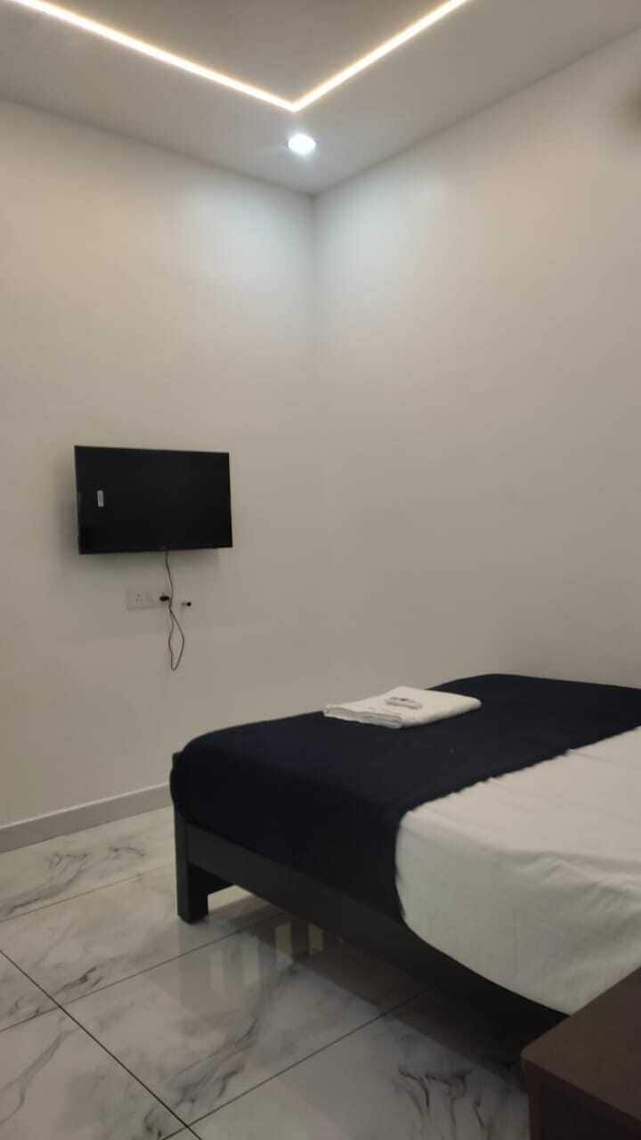Quarto com cama, televisão de tela plana na parede e luminária no teto.