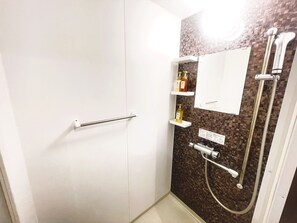 Un baño con ducha, toallero y espejo.
