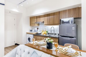 Eine moderne Küche mit Holdekor, einem Edelstahlkühlschrank und einem Essbereich mit Tisch für zwei Personen.