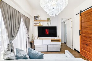Ein modernes Wohnzimmer mit einem großen Flachbildfernseher, einer Couch und einer Holztür.