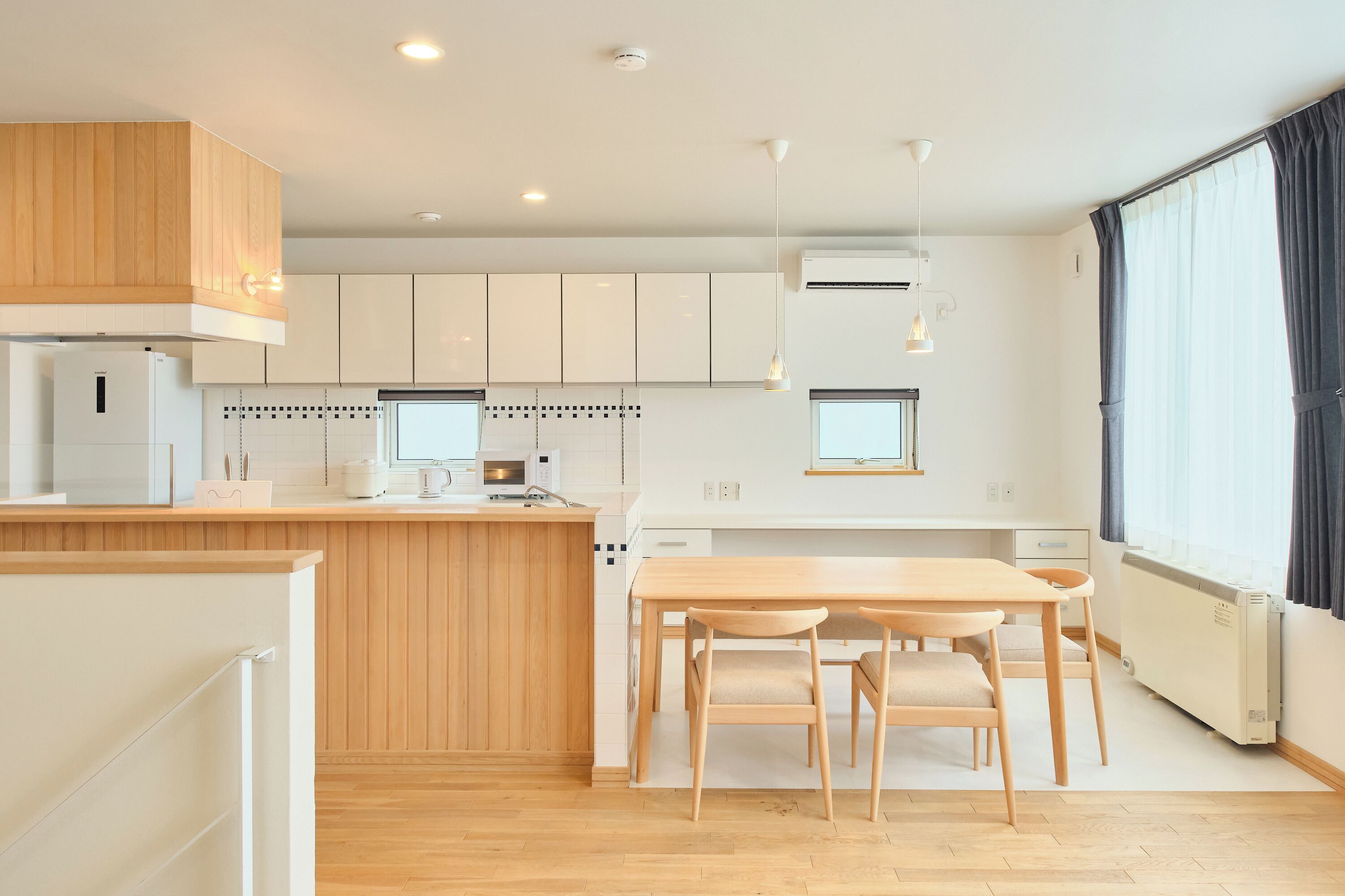 Una cocina moderna con armarios de madera, una isla central y un comedor con mesa y sillas.