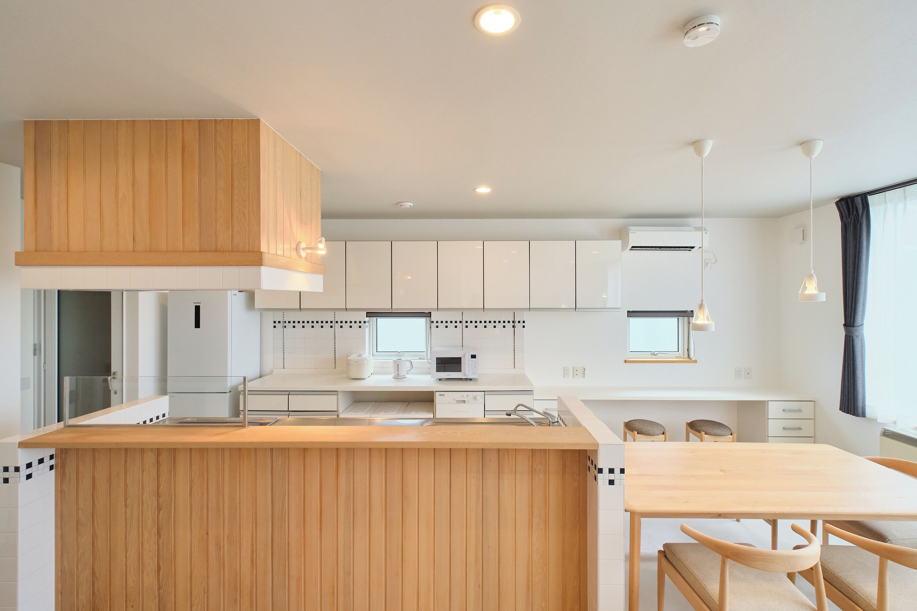 Una cocina moderna con armarios de madera, una isla central y un comedor con mesa y sillas.