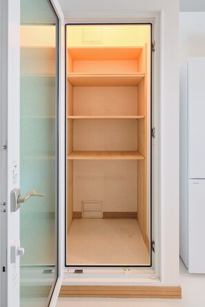 A room with a sliding door leading to a storage space with multiple shelves.