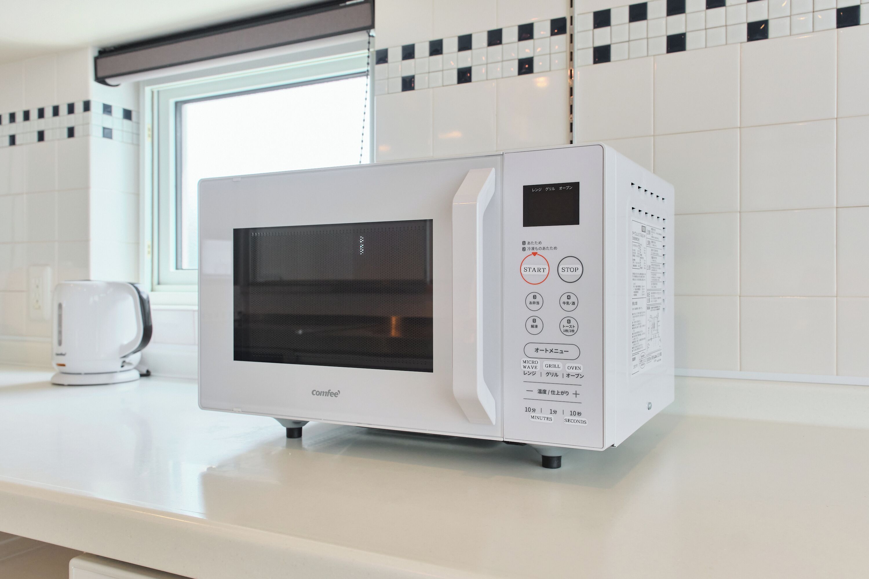 A white microwave oven with a digital display and control panel on a kitchen counter.