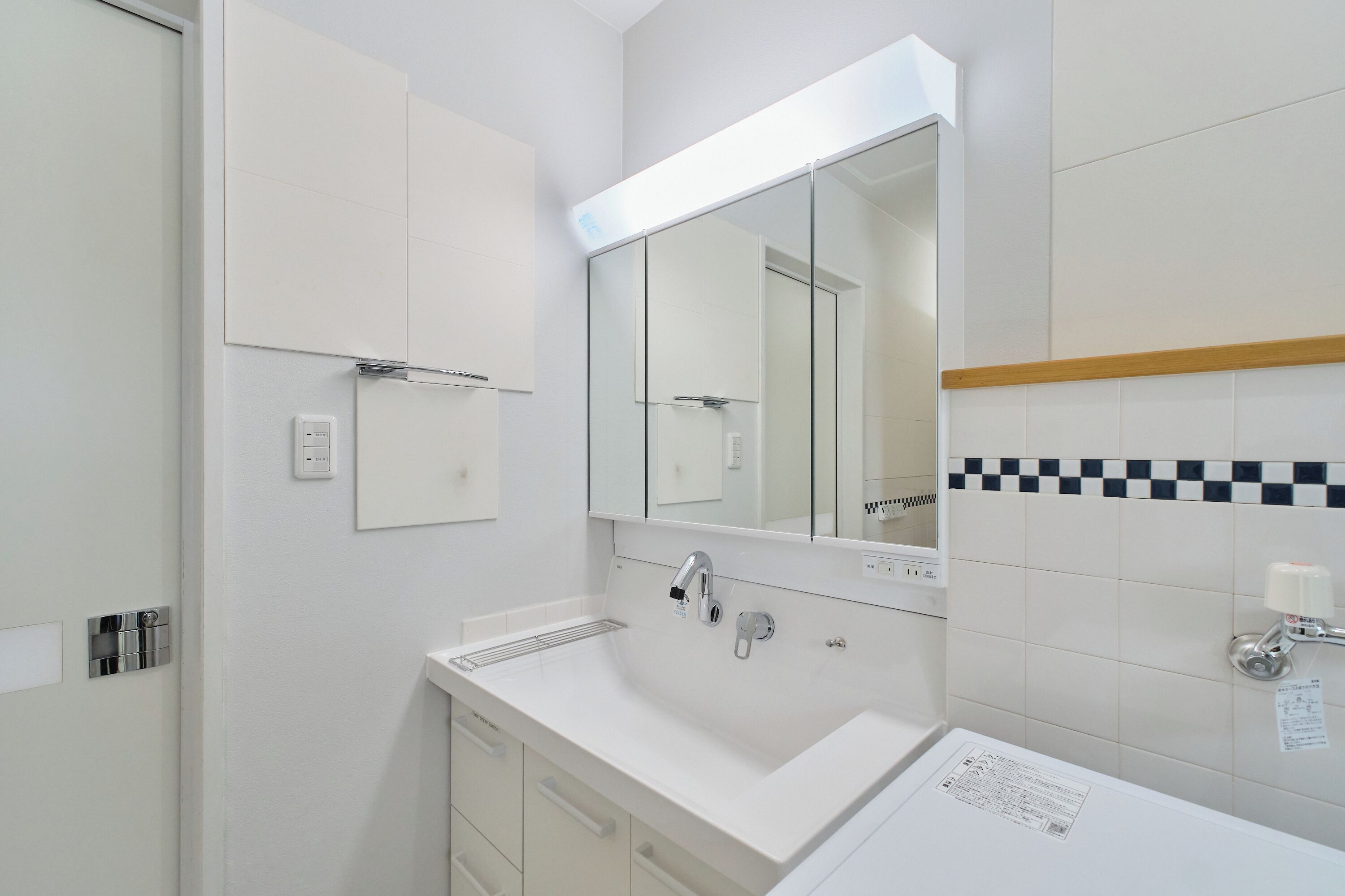 A modern bathroom with a white sink, a mirror, and a cabinet.