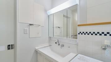 A modern bathroom with a white sink, a mirror, and a cabinet.