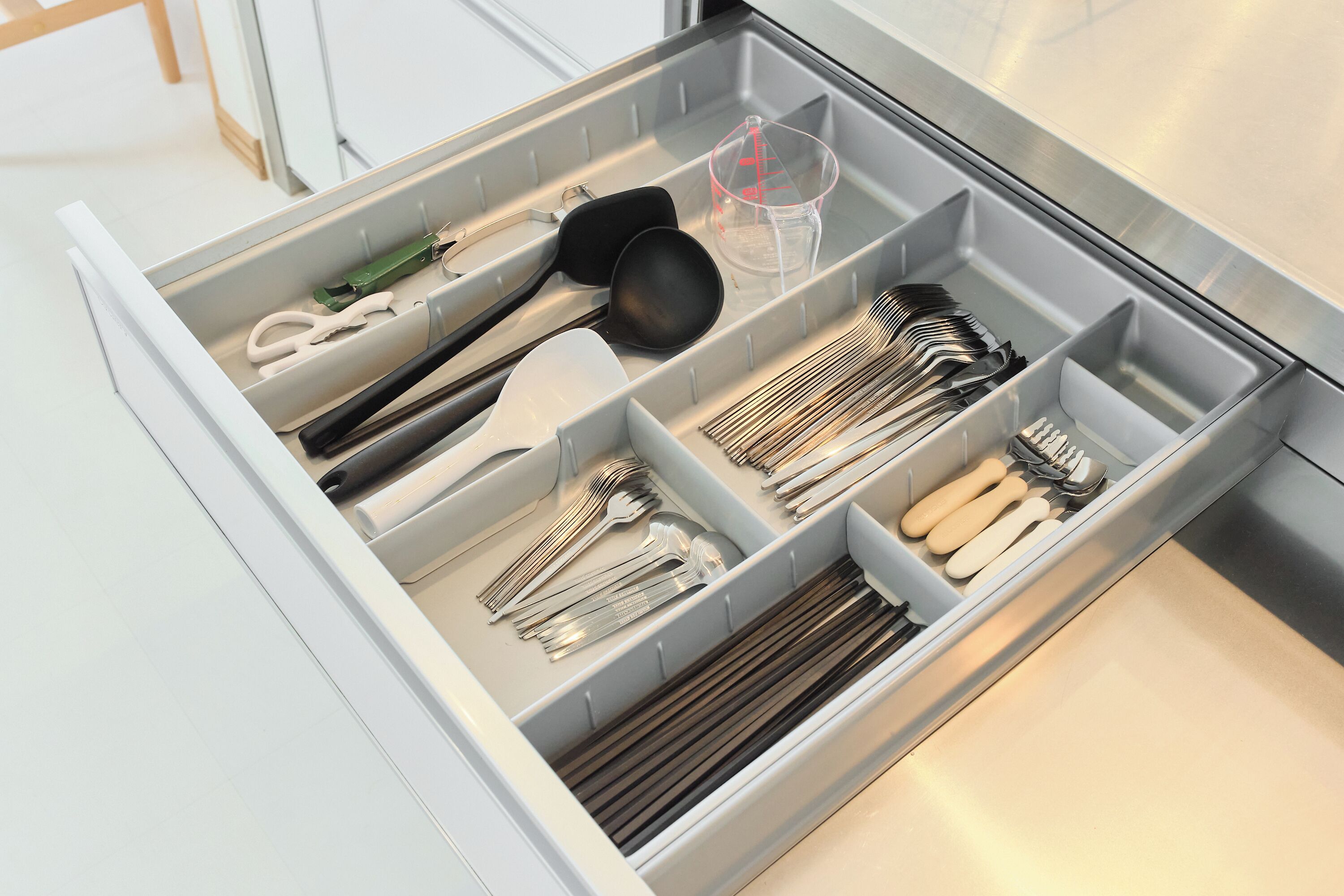 Un cajón de cocina con utensilios y utensilios de cocina organizados en compartimentos.