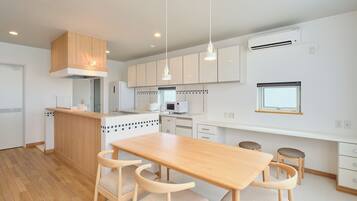 A modern kitchen with wooden cabinetry, a central island, pendant lighting, and a dining area with a wooden table and chairs.