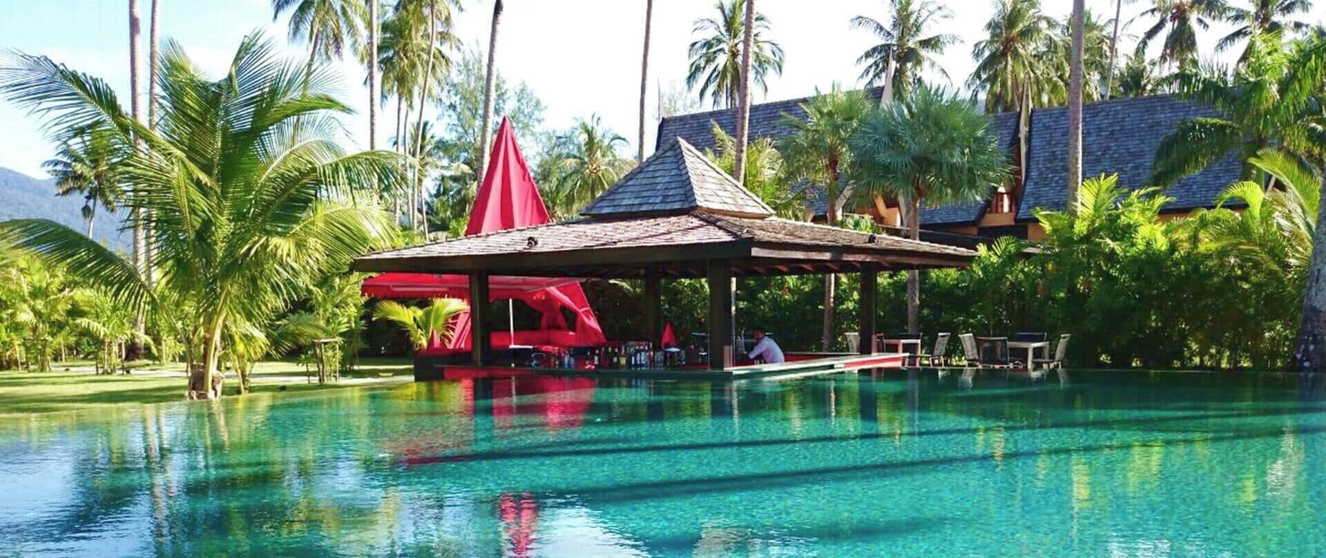 A swimming pool with a red-roofed pavilion and lounge chairs.