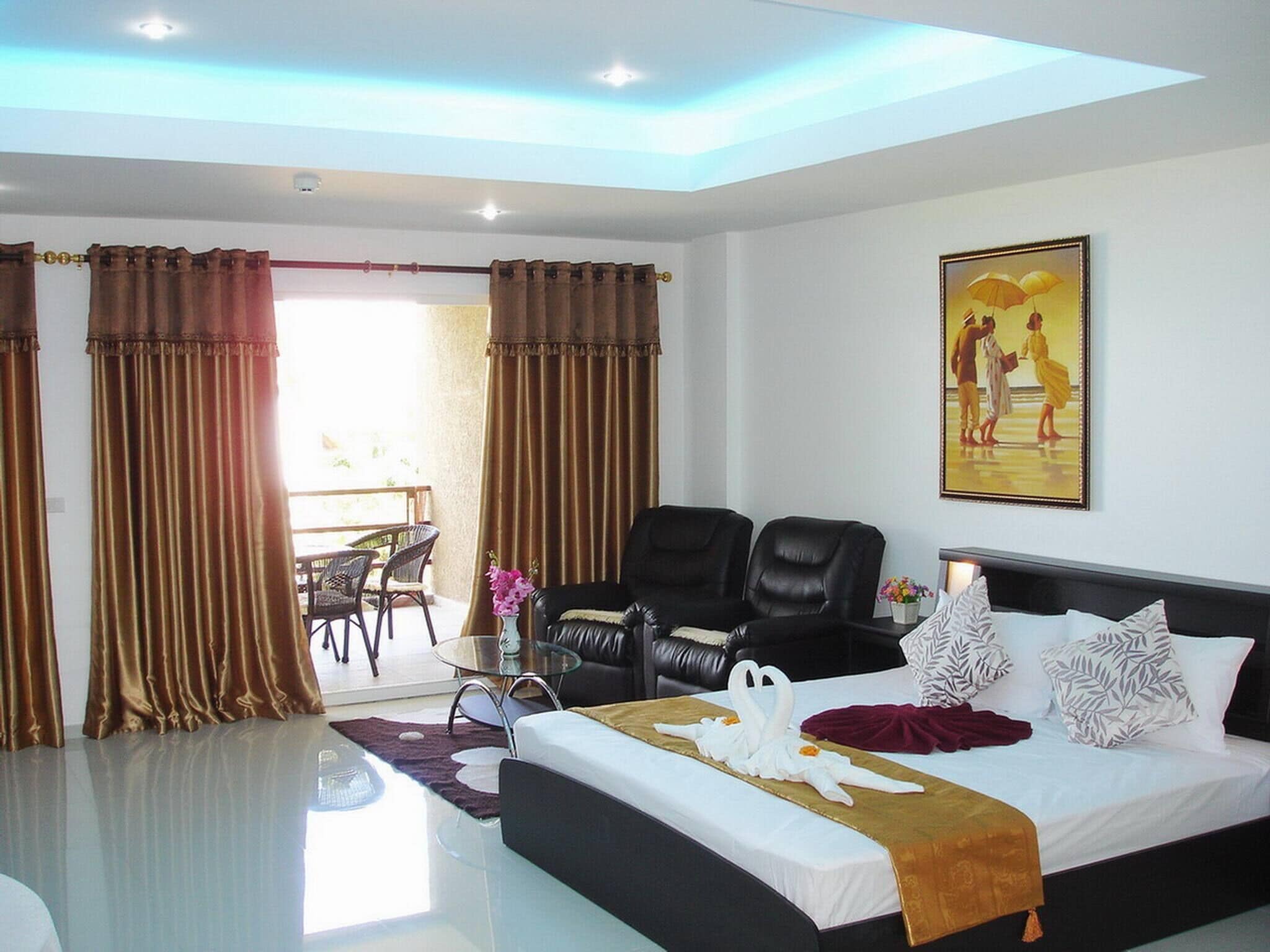A hotel room with a bed, two black leather chairs, a dining table with chairs, and a painting on the wall.