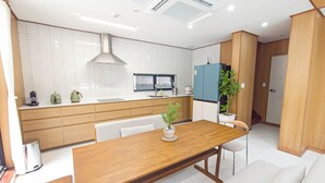 A modern kitchen with a wooden dining table, white cabinets, and a built-in stove.