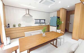 A modern kitchen with a wooden dining table, white cabinets, and a built-in stove.