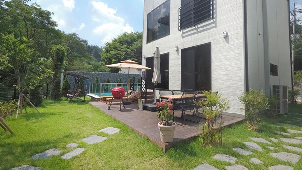 A modern two-story building with a patio area featuring outdoor furniture and a barbecue grill.