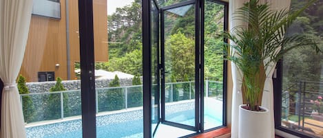 A modern interior with a large sliding glass door leading to an outdoor swimming pool area.