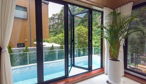 Un intérieur moderne avec une grande porte-fenêtre coulissante donnant accès à un espace extérieur avec piscine.