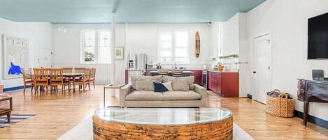 A spacious living room with a round coffee table, a sofa, and a dining area with wooden chairs.