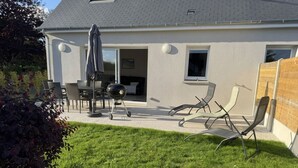 En boligejendom med terrasse, havemøbler og græsplæne.