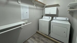 A laundry room with two washing machines, a drying rack, and a cabinet.
