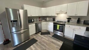 Cocina moderna con armarios blancos, electrodomésticos de acero inoxidable y encimera negra.