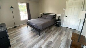 Un dormitorio con cama, mesitas de noche, una lámpara, un armario y una puerta.