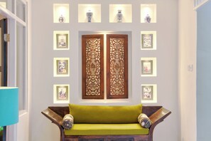 A room with a wooden bench, decorative panels, and framed pictures on the wall. - Selasih Beach House (Badung)