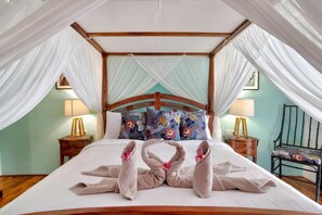 A four-poster bed with a canopy, floral pillows, and towels arranged on the bed. - Selasih Beach House (Badung)