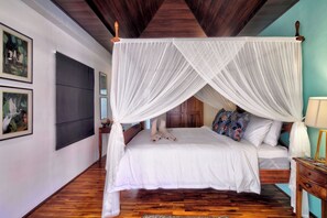 Un dormitorio con cama a dosel, suelo de madera y obras de arte en las paredes.