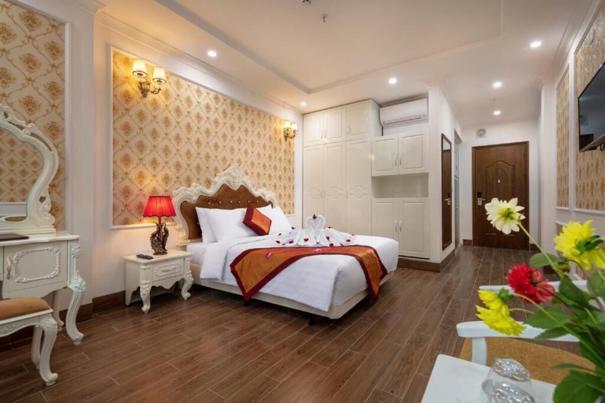 Una habitación de hotel con una cama grande, un armario blanco y un espejo.