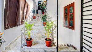Una escalera de mármol con plantas en macetas, barandilla de metal y una puerta con ventana.