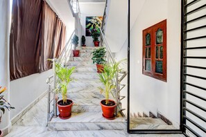 A marble staircase with potted plants, a metal railing, and a door with a window.