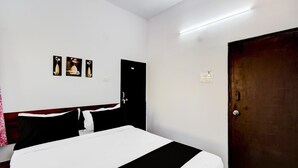 Una habitación de hotel con una cama, un armario y tres cuadros colgados en la pared.
