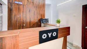 Una mesa de recepción con un cartel que dice 'OYO' y un letrero que indica 'CUARTO DE PERSONAL' sobre una puerta de madera.