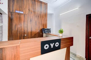 A reception desk with a sign reading 'OYO' and a 'STAFF ROOM' sign above a wooden door.