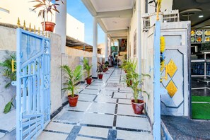 A corridor with tiled flooring, potted plants, and a blue gate.