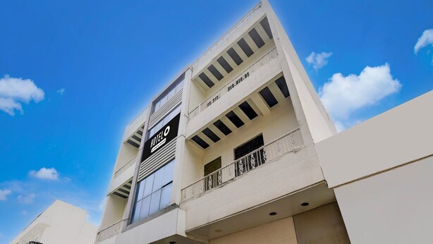 Un hotel de varios pisos con un letrero llamativo, balcones y un cielo despejado.