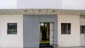 Entrada de un edificio moderno con puerta de vidrio, una escalera y un ventanal con barrotes de metal.