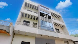 Un hotel de varios pisos con un llamativo letrero 'HOTEL' en la fachada, balcones con barandas y un cielo despejado al fondo.