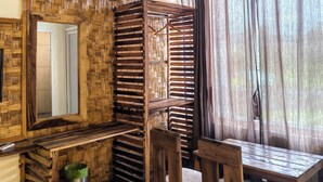 Una stanza con una panchina in legno, un tavolo, uno specchio e una finestra con tende.