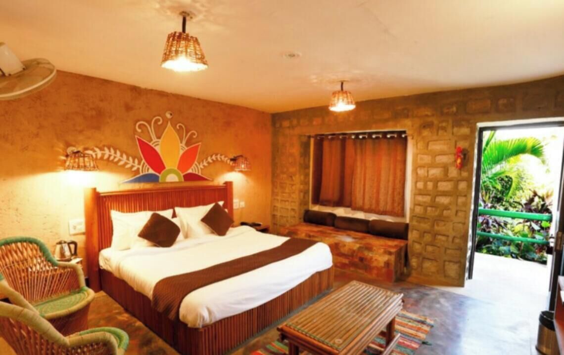 Habitación de hotel con cama, una silla, una mesita y vistas al exterior.