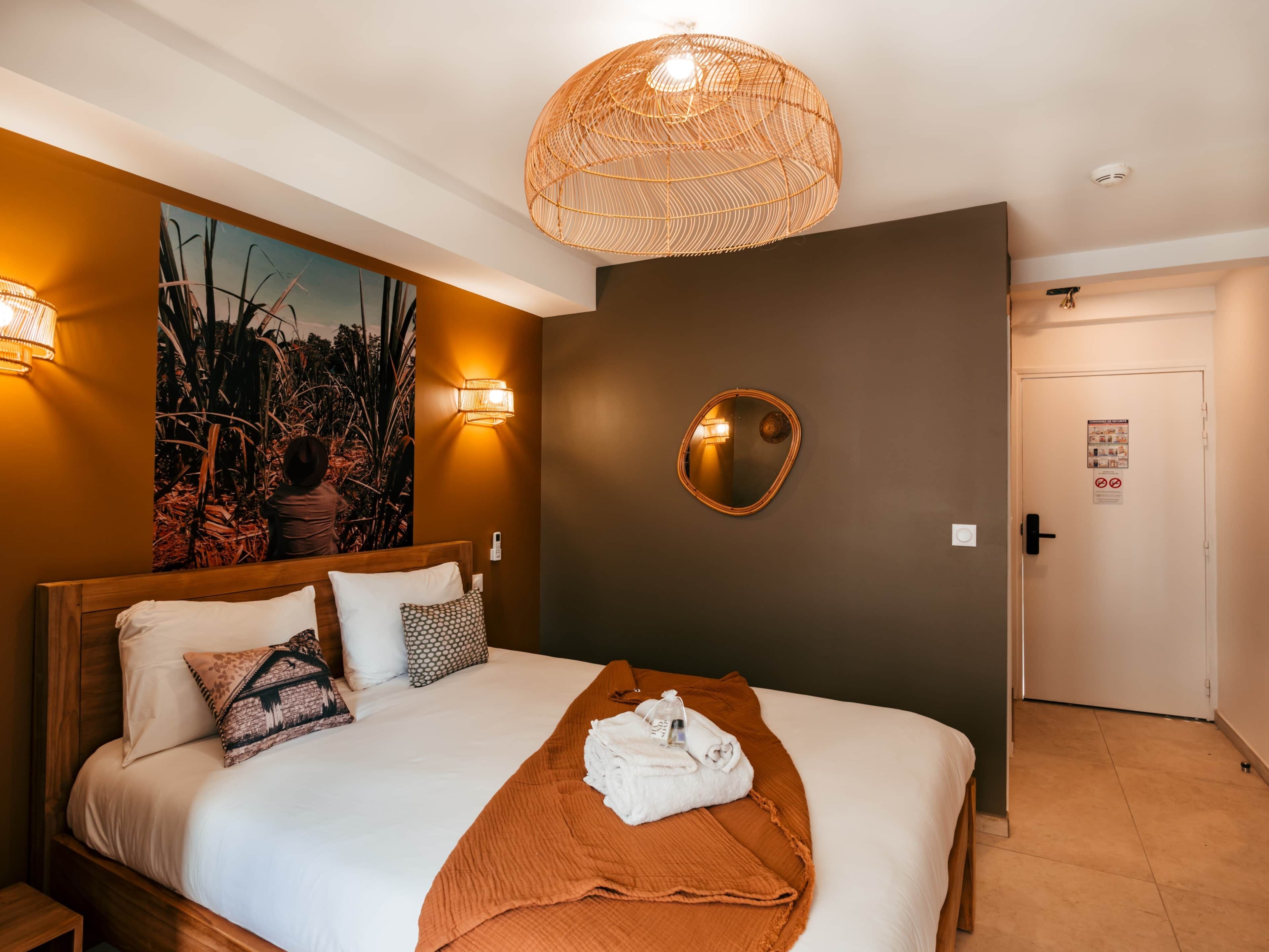 Habitación de hotel con cama, espejo en la pared, un cuadro y una puerta con un cartel.