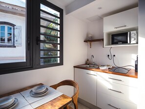 Eine kleine Küche mit Fenster, einer Mikrowelle und einem Spülbecken.