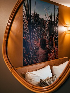 Ein Zimmer mit einem Bett, einem Kissen, einer Wandleuchte und einem gerahmten Bild.