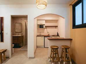A compact kitchen with a microwave, sink, and stools. - Pointe au Sel Apartment - L'Escale Bleue, Saint-Leu, Réunion (Saint-Leu)